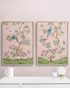 pair of 2 framed pink and green chinoiserie wall art prints with botanical illustrations featuring birds, butterflies, and flowers hung on wall