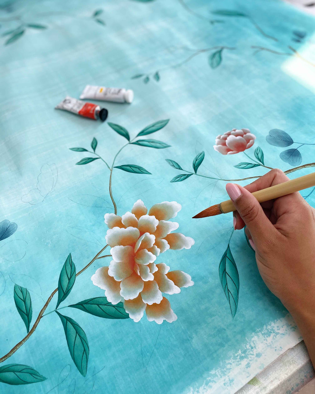 A close up of Diane Hill holding a Chinese paintbrush as she creates a silk scarf design in collaboration with Sarah Flint