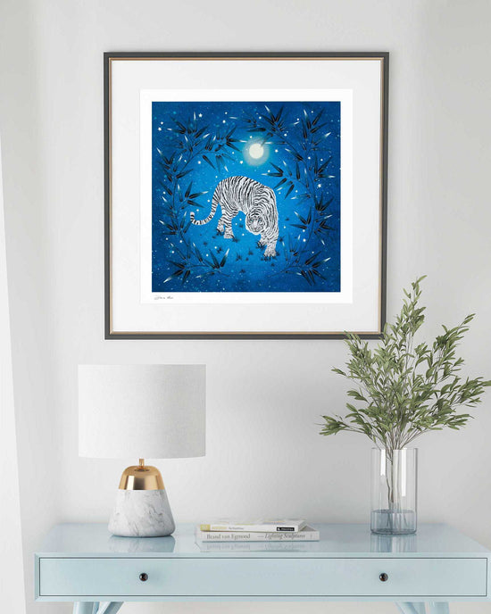 framed blue vintage-style chinoiserie wall art print featuring a white tiger on a blue starry background hung on wall