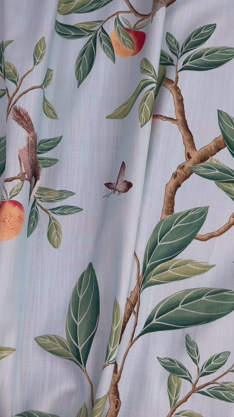 close up of blue botanical fabric featuring chinoiserie style birds, branches, and butterflies