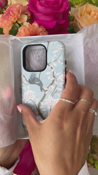 luxury chinoiserie phone case with botanical illustrations being applied to an iPhone