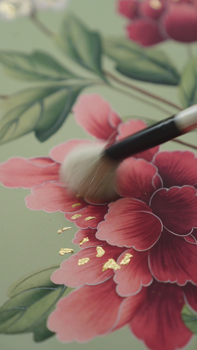 hand holding paintbrush applying 24 carat gold and stamp to chinoiserie floral art prints