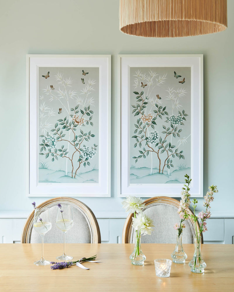 pair of two pebble blue framed chinoiserie wall art prints featuring butterflies, flower branches, and bamboo hung on wall