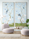 pair of 2 framed blue chinoiserie wall panel prints with botanical illustrations featuring birds, butterflies, and flowers hung on wall