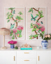 pair of framed Chinoiserie style art prints featuring butterflies and pink flowers on a pastel pink background hung on wall