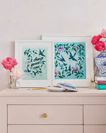 two blue framed chinoiserie wall art print featuring vintage inspired birds surrounded by leaves and flowers on set of drawers