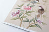 close up of blush pink chinoiserie wall art print featuring vintage style birds, butterfly and flower branches with a bamboo background