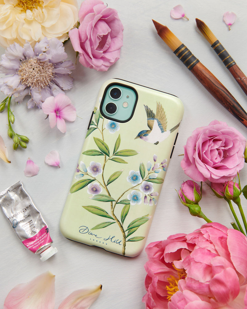 The Limited Edition Carrie phone case by Diane Hill. Carrie features a pretty little bird swooping above branches of jewel-toned blossom for a fresh, contemporary feel. A styled flatlay set with peonies and paintbrushes