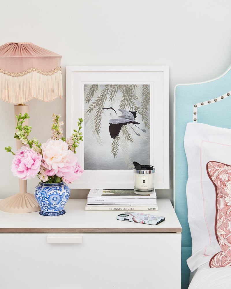 framed Japanese-style chinoiserie wall art print featuring heron and wisteria on silver background on bedside table