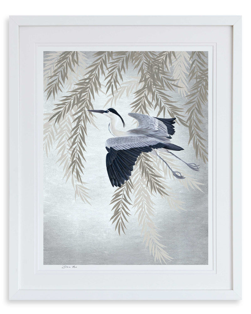 Celeste Art Print, framed in a classic white frame. The Celeste art print by Diane Hill features an elegant heron in flight against a backdrop of weeping willow, with silvery blue tones for a restful feel