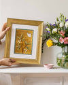 framed chinoiserie wall art print featuring vintage Chinese-style butterfly and flower branch on gold background on mantle