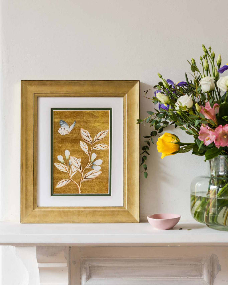 framed chinoiserie wall art print featuring vintage Chinese-style butterfly and flower branch on gold background on mantle