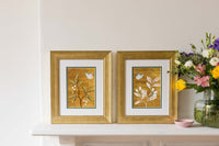 pair of framed chinoiserie wall art print featuring vintage Chinese-style butterfly and flower branch on gold background on mantle