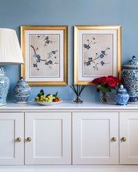 pair of framed chinoiserie wall art prints featuring Japanese-style cherry blossom branches on silver background hung on wall