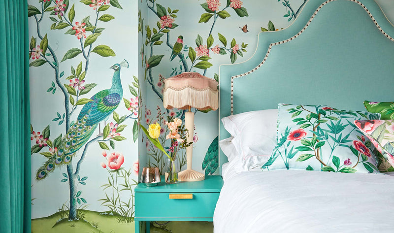 Florence chinoiserie wallpaper by diane hill and harlequin blue colourful with birds and butterflies big blue headboard and chinoiserie cushions on bed