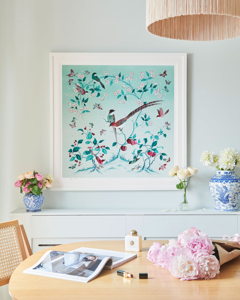 framed blue chinoiserie art print featuring colourful birds on blossom branch, butterflies and fruit hung on wall