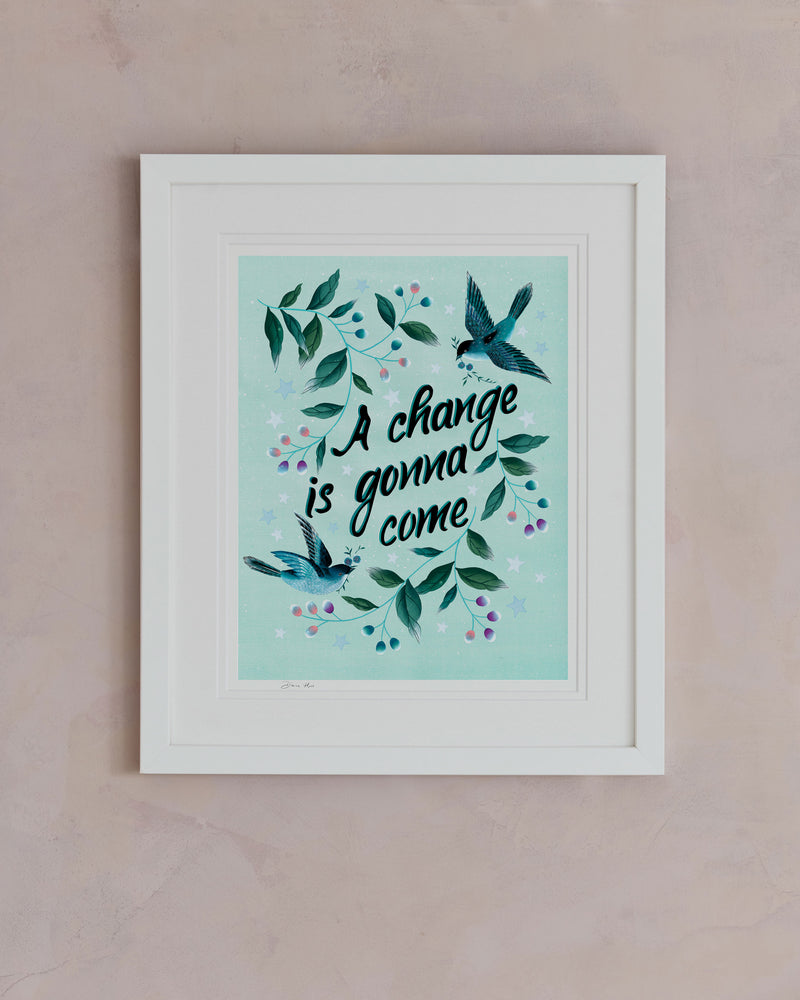 framed blue vintage-style chinoiserie wall art print featuring birds and branches with the quote 'a change is gonna come' hung on wall