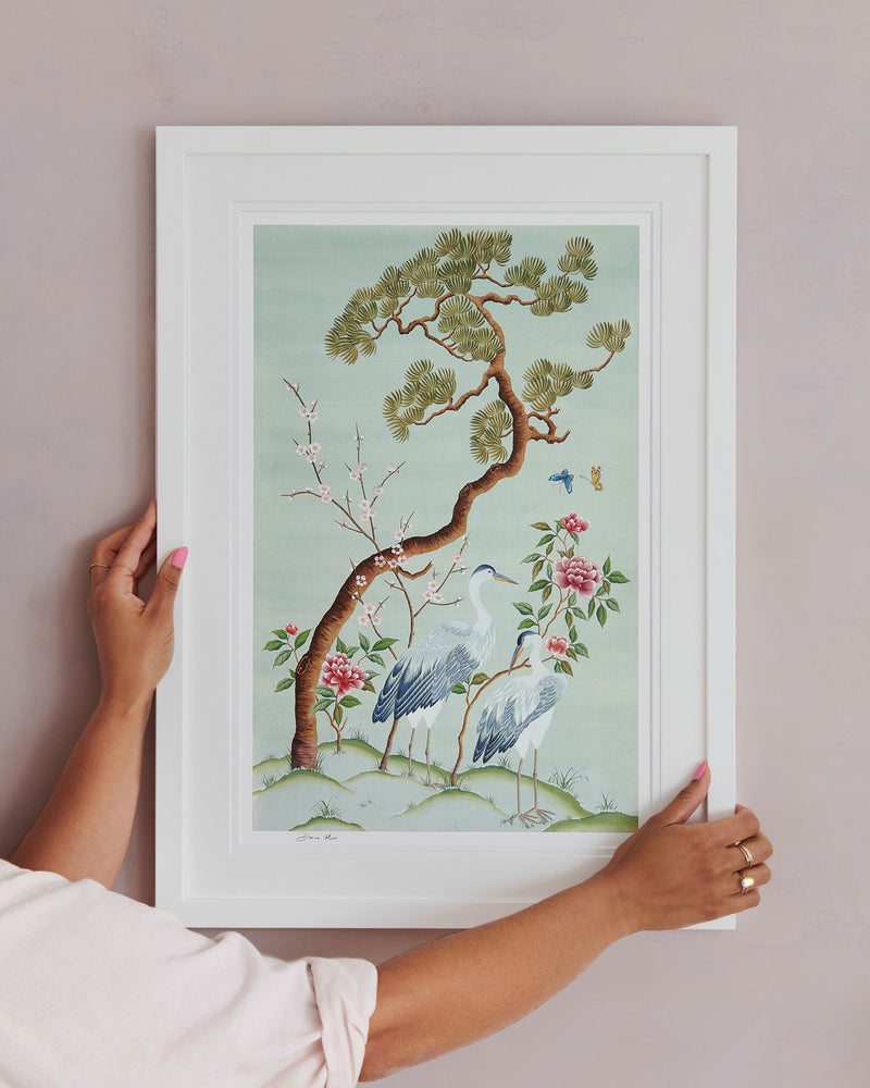 Diane Hill hangs her Susan art print, framed in a classic white frame against a pink wall. Featuring herons, butterflies, blossom and peonies, this modern chinoiserie print by Diane Hill is inspired by a beautiful antique painting found in The National Trust’s Saltram House. 