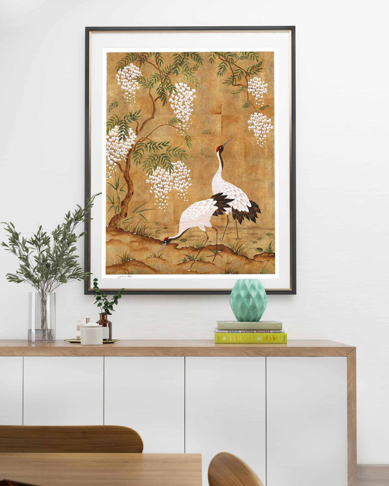 framed Japanese style chinoiserie wall art print featuring cranes and wisteria tree on gold background hung on wall