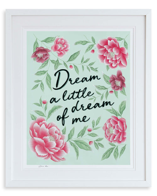 Dream a Little Dream charity art print by Diane Hill in blue, framed in a classic white frame. This charity art print features hand painted lyrics set against a blue background, woven with delicate sage green leaves and blooming pink peonies