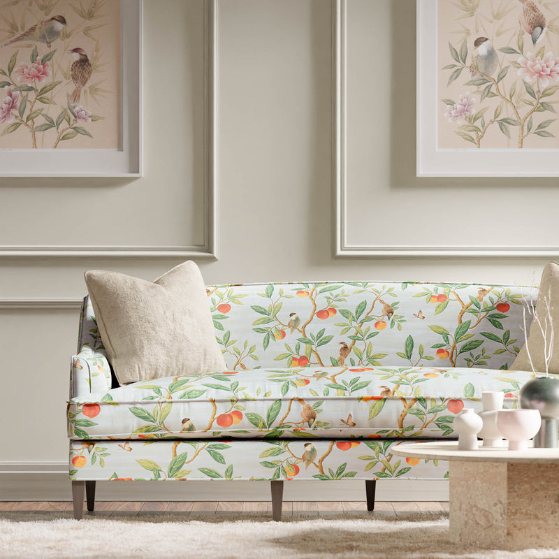 blue botanical fabric featuring chinoiserie style birds, branches, and butterflies on sofa in modern living room