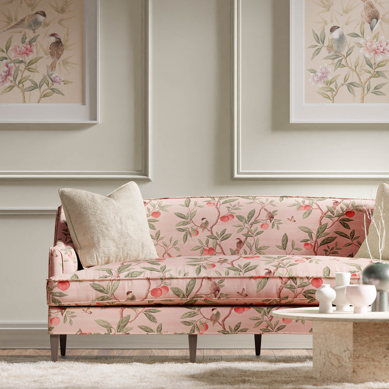 pink botanical fabric featuring chinoiserie style birds, branches, and butterflies on sofa in modern living room