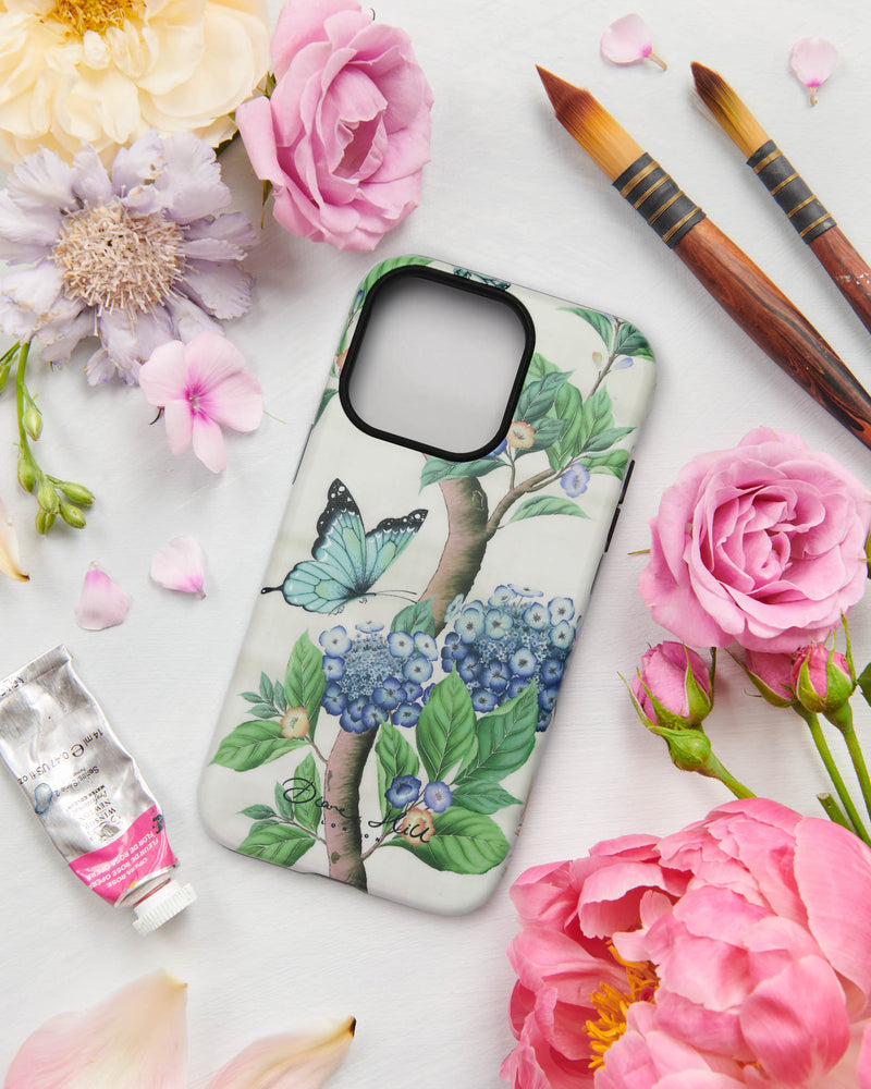 A floral butterfly phone case by Diane Hill featuring hydrangea flowers and lush leaves in  neutral and blue tones