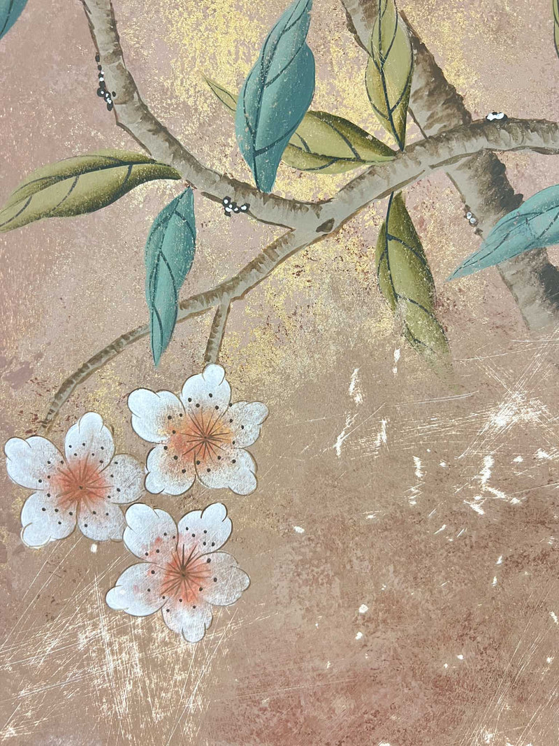 close up of framed vintage style chinoiserie painting featuring a bird and blossom branch on a distress mottled bronze and gold background