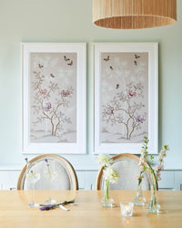 The Lilly and Mariya art print in ballet pink, framed side by side in a dining room in a classic white frame. A celebration of butterflies, bamboo and botanicals, Lilly is a beautiful modern chinoiserie art print which was originally hand-painted onto pure silk, featuring delicate leaves and an abundance of butterflies 