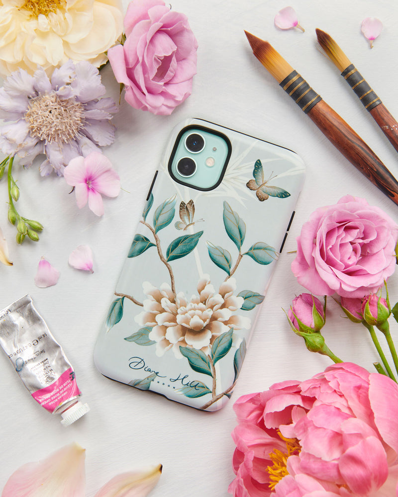 The Lilly phone case by Diane Hill. A celebration of butterflies, bamboo and botanicals, Lilly is a beautiful modern chinoiserie design which was originally hand-painted onto pure silk, featuring delicate leaves and an abundance of butterflies. A styled flatlay set with peonies and paintbrushes