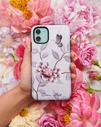 hand holding pink luxury phone case featuring vintage style butterfly and flower branches with a bamboo background