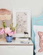 soft pink framed chinoiserie wall art print featuring butterflies, flower branches, and bamboo hung on wall