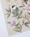 close up of blush pink chinoiserie wall art print featuring vintage style birds, butterfly and flower branches with a bamboo background