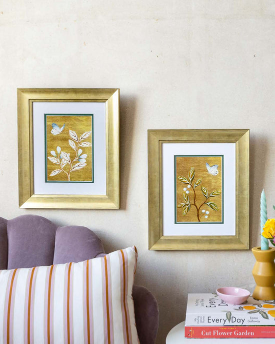 pair of framed chinoiserie wall art print featuring vintage Chinese-style butterfly and flower branch on gold background hung on wall