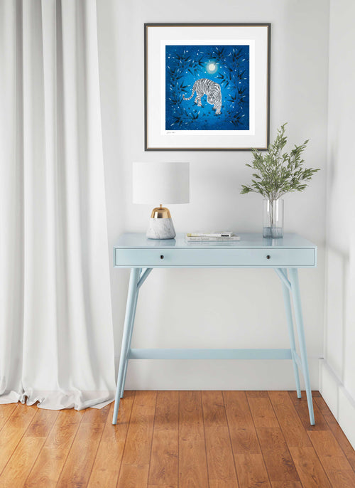 Diane Hill Aniya art print featuring a white indian tiger on a vibrant blue background with bamboo. This art print is displayed framed above a console table.